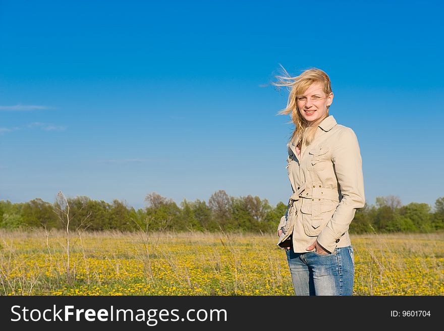 The young smiling girl standing on field. The young smiling girl standing on field