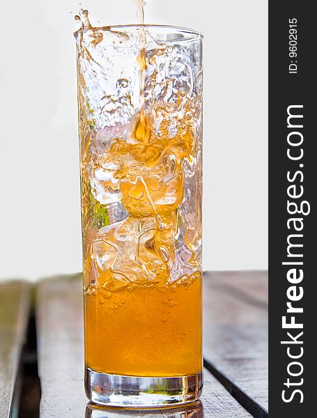 Cold orange drink poured into glass with ice cubes. Cold orange drink poured into glass with ice cubes