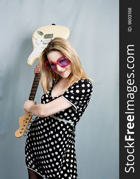 Blonde with guitar smiling isolated over grey background