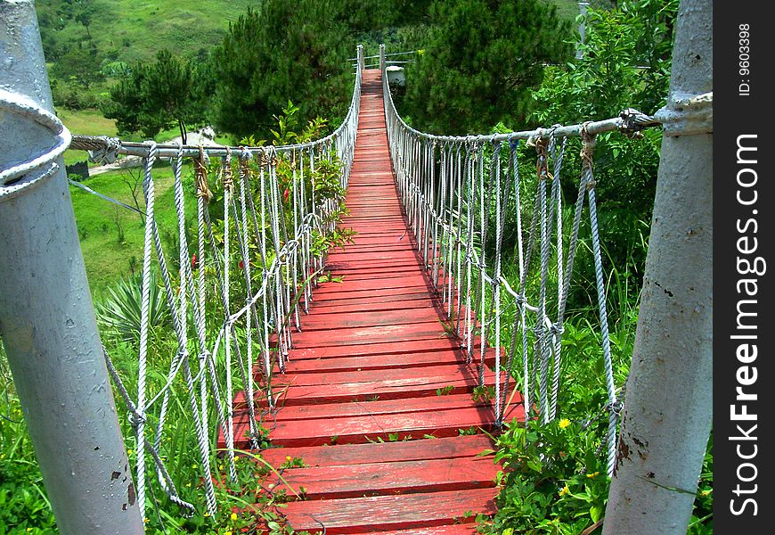 A photo of a Wooden hanging Bridge with steel post with steel cable cord