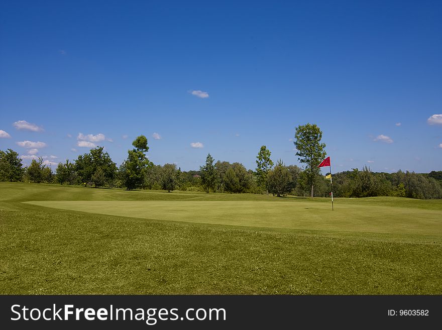 Red flag on hole, golf course tee