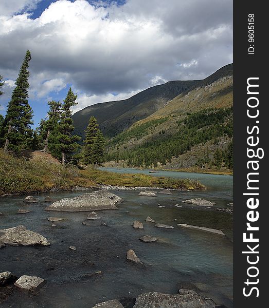 Quiet water of lake, cedar wood on coast, mountains, the sky, a cloud. The river and a train of lakes Small Kulagash, Mountain Altai, July 2008. Quiet water of lake, cedar wood on coast, mountains, the sky, a cloud. The river and a train of lakes Small Kulagash, Mountain Altai, July 2008.