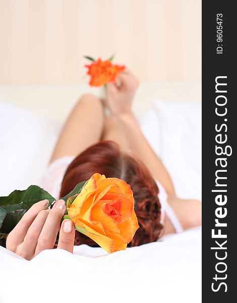 Young woman in bed with orange roses. Young woman in bed with orange roses