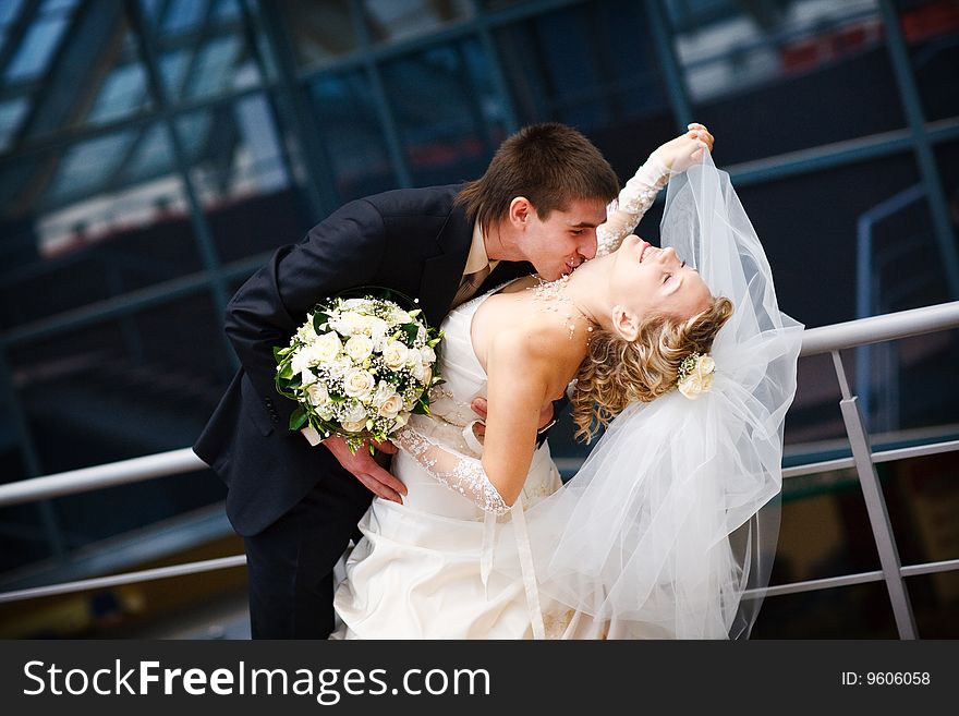 Groom and bride kiss under the glass ceiling