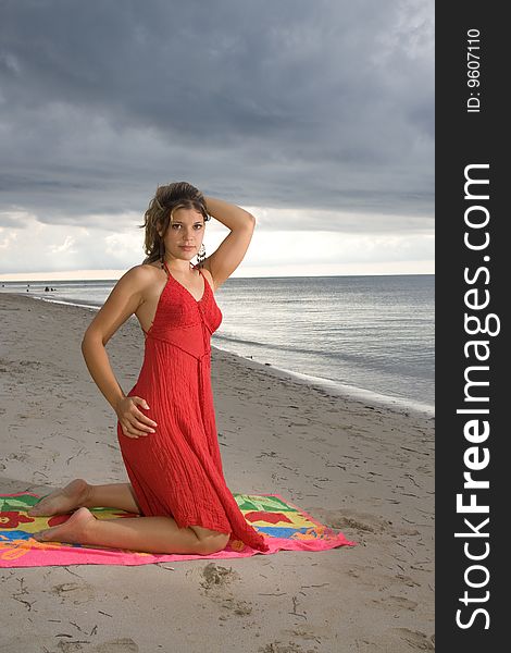 Girl with red dress on a towel and her hand in the head. Girl with red dress on a towel and her hand in the head