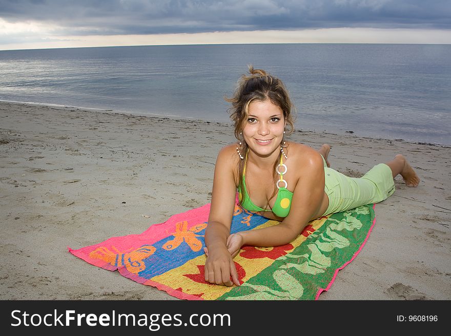 Beautiful lady smiling in the beach, laying on a coloured towel (II). Beautiful lady smiling in the beach, laying on a coloured towel (II)
