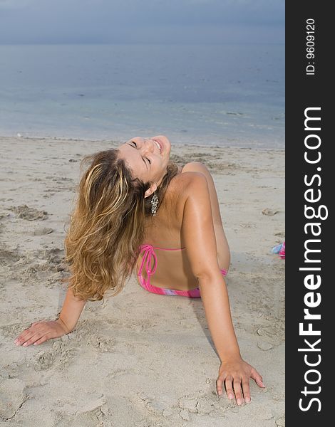 Beautiful blond lady wearing a pink bikini, smiling in the beach