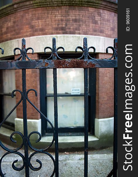 Rusted iron fence in front of a brownstone house in Brooklyn, with a window in the background. Rusted iron fence in front of a brownstone house in Brooklyn, with a window in the background