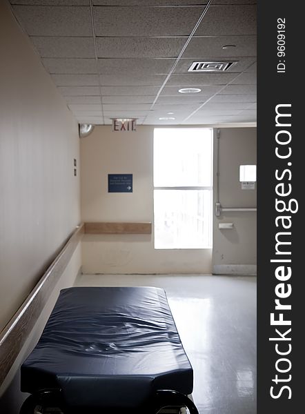 Uncovered stretcher at the hospital corridor with an emergency exit in the background