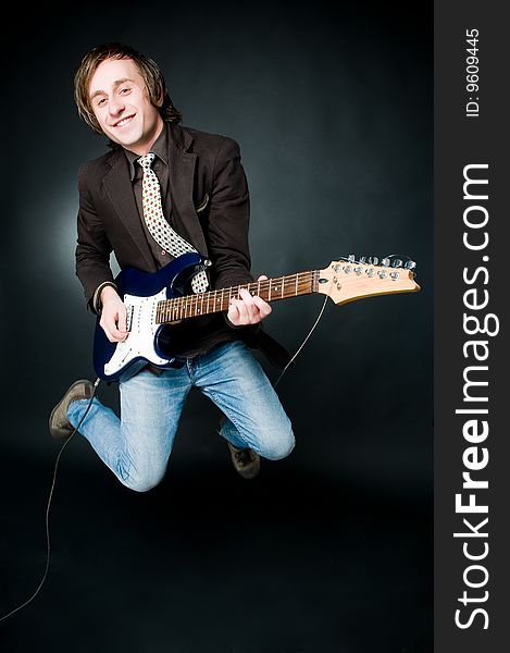 Jumping man with electro guitar, studio shot