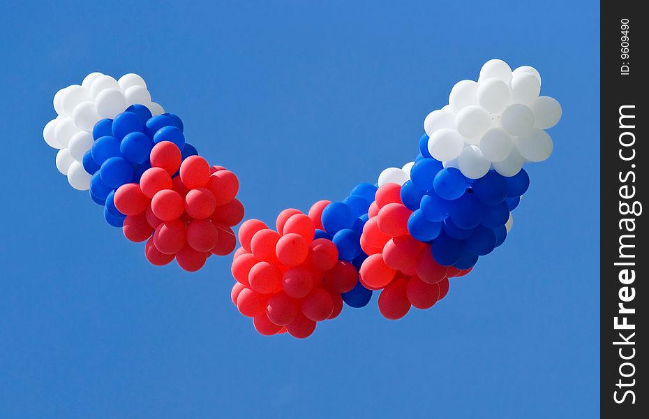 Red, white and blue balloons on a blue sky background