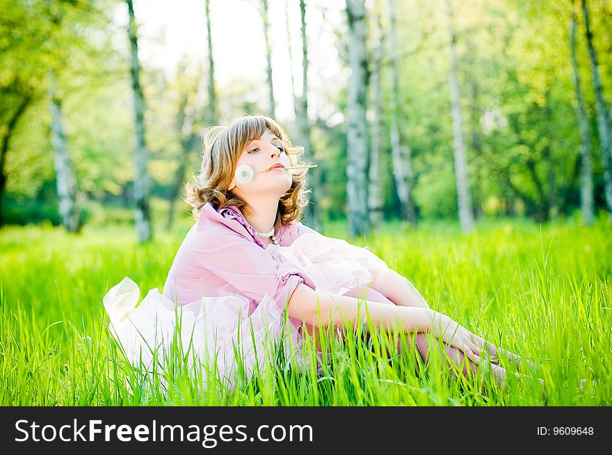 Attractive girl with dandelion in perfect green grass