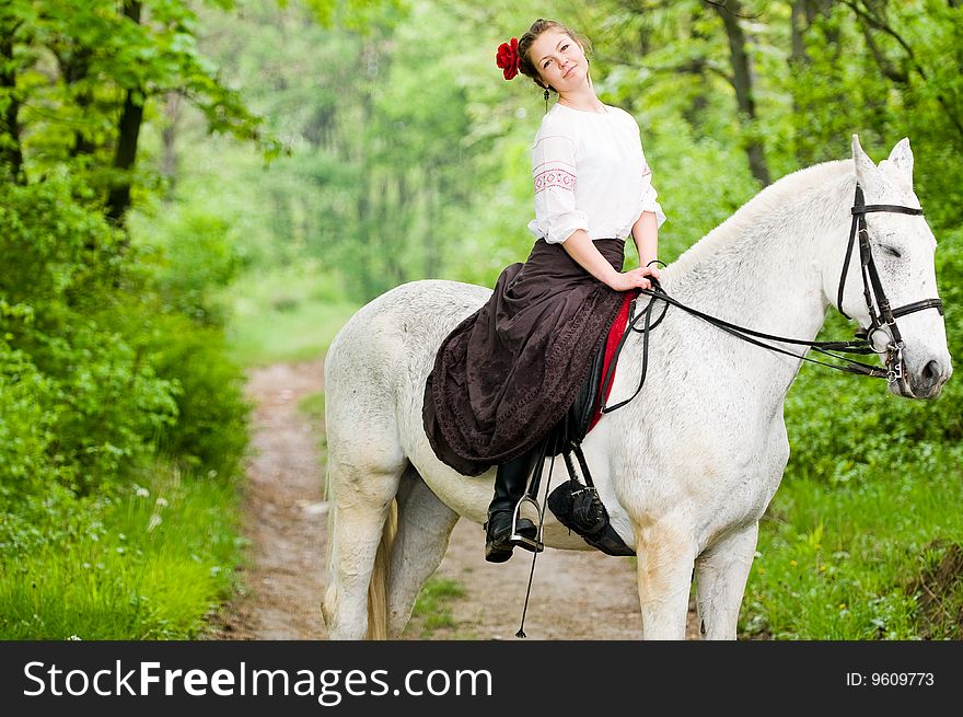 Cheerful girl riding horse in the forest