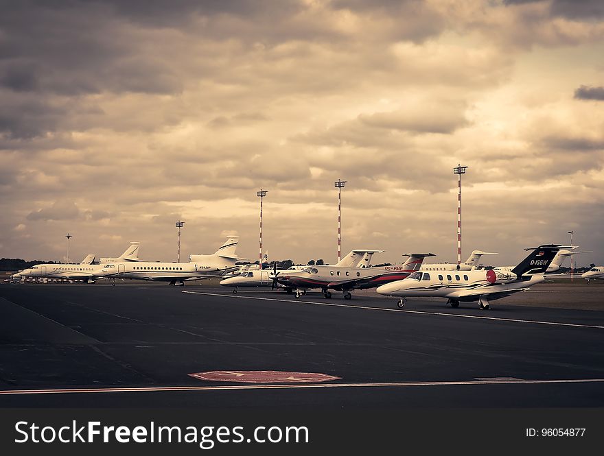 Airbus and several small private jet aircraft parked on the apron at a commercial airport, cloudy overcast sky. Airbus and several small private jet aircraft parked on the apron at a commercial airport, cloudy overcast sky.