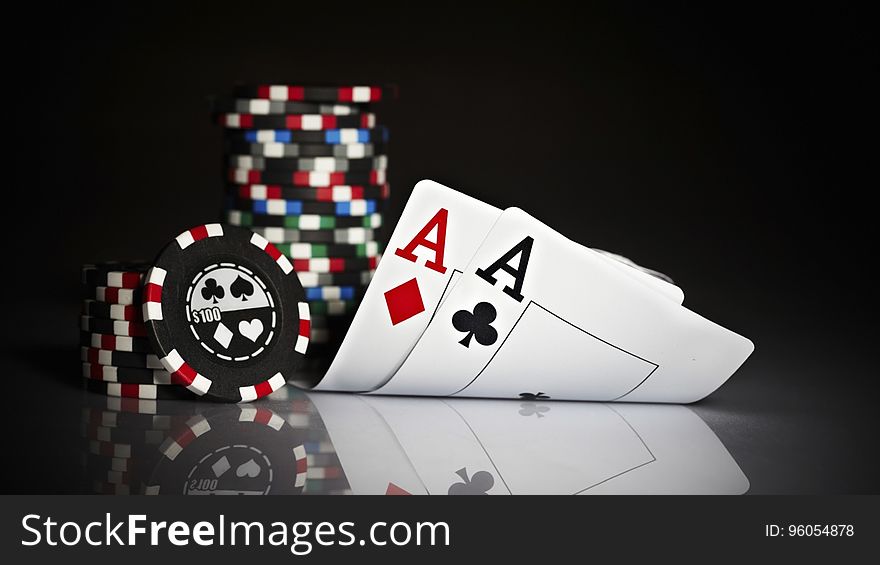 A pair of aces and stacks of gambling chips reflecting on a glass surface.