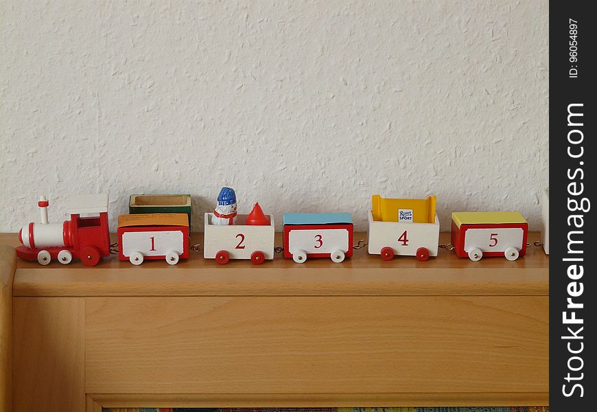 A colorful toy train on a wooden shelf.