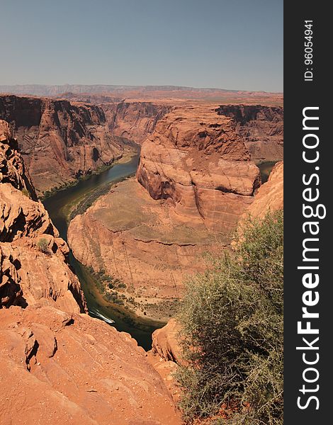 Deep river canyon cut through landscape composed mostly of red sandstone, pale blue sky. Deep river canyon cut through landscape composed mostly of red sandstone, pale blue sky.