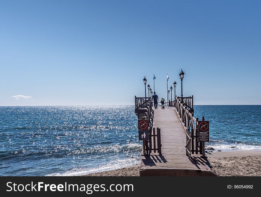 Wooden boardwalk and pier on waterfront on sunny day. Wooden boardwalk and pier on waterfront on sunny day.