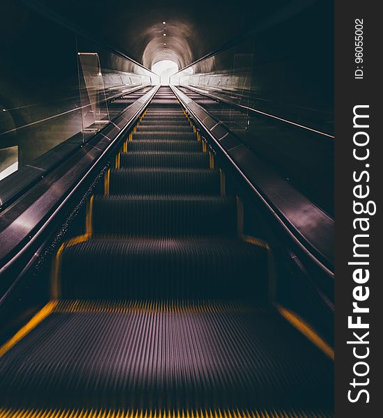 A long escalator leading in and out from a subway station. A long escalator leading in and out from a subway station.