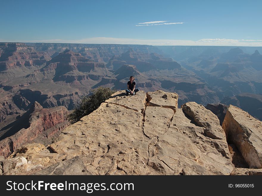 A person sitting on the precipice at the Gran Canyon.