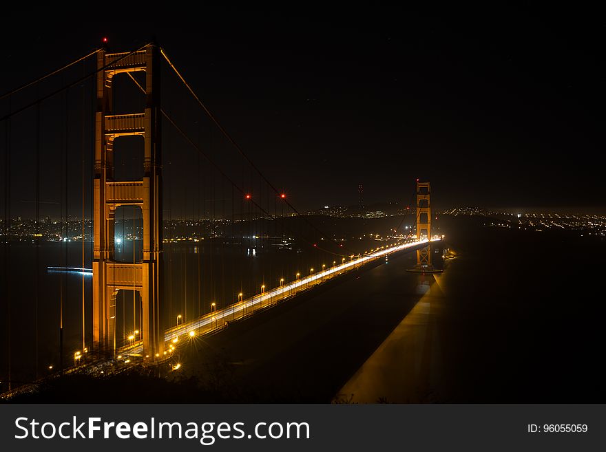 Aerial over Golden Gate Bridge, San Francisco, California illuminated at night with distant city skyline. Aerial over Golden Gate Bridge, San Francisco, California illuminated at night with distant city skyline.