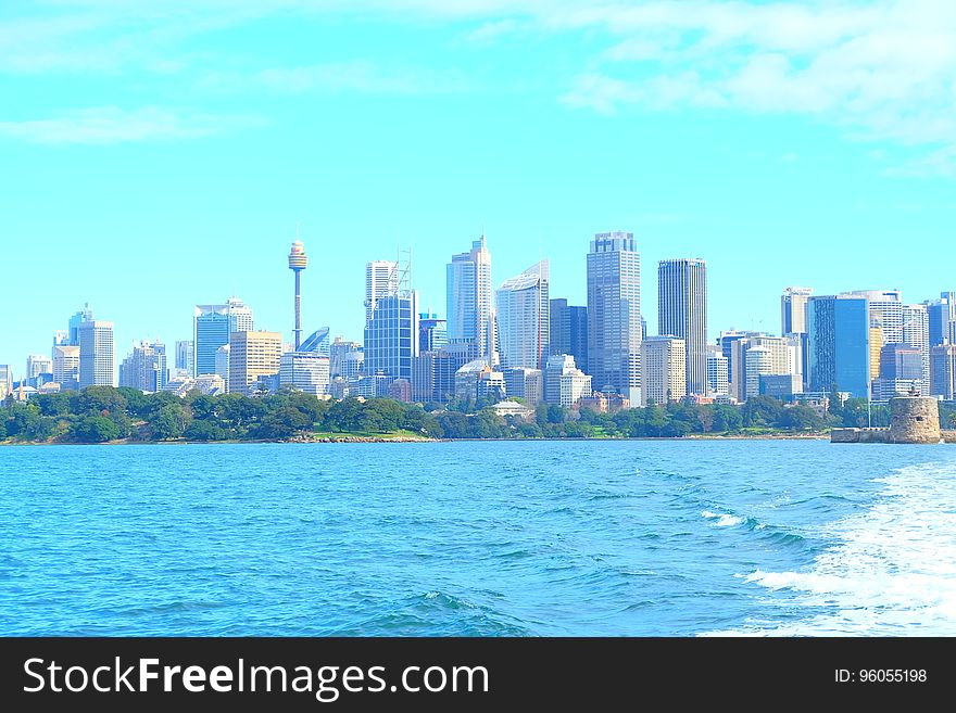 Skyline of modern city with high rise buildings along waterfront on sunny day. Skyline of modern city with high rise buildings along waterfront on sunny day.