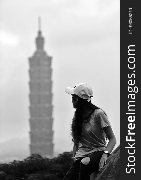 Woman looking back at high rise tower in distance in black and white. Woman looking back at high rise tower in distance in black and white.