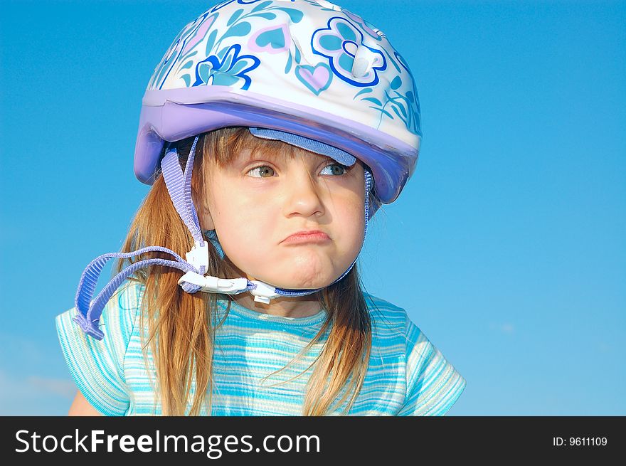 Grimacing girl with a helmet on her head on the blue background