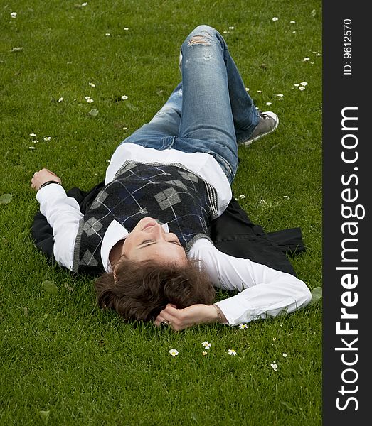 Pretty student-looking woman lays on the grass in the city park. Pretty student-looking woman lays on the grass in the city park