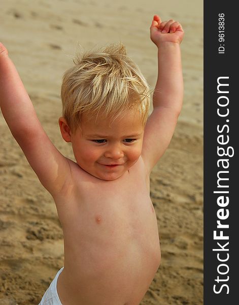 A little 2 year old boy holding his arms up in happiness. A little 2 year old boy holding his arms up in happiness