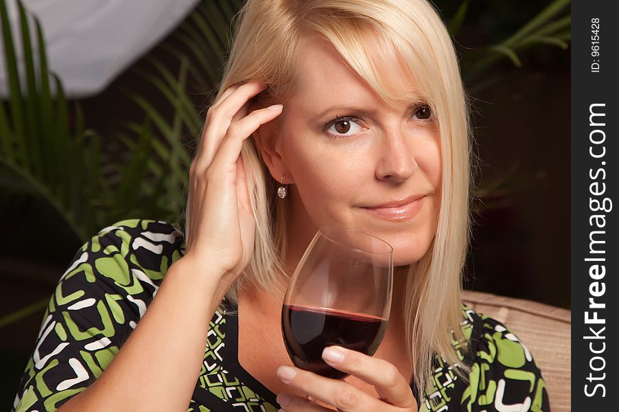 Beautiful Blonde Woman Smiling at an Evening Social Gathering Tasting Wine. Beautiful Blonde Woman Smiling at an Evening Social Gathering Tasting Wine.