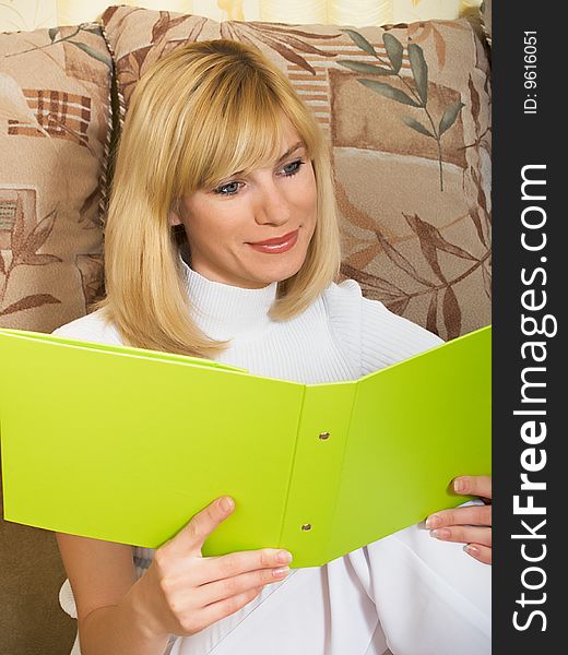 The beautiful girl sits at home with a folder for documents. The beautiful girl sits at home with a folder for documents