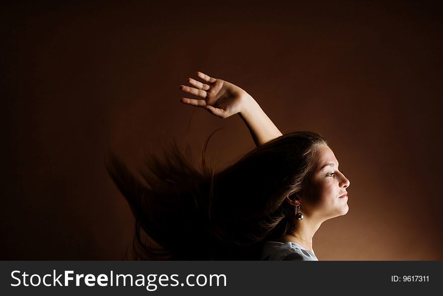 Fashion portrait of a young woman with hair lightly fluttering in the wind on a dark background. Fashion portrait of a young woman with hair lightly fluttering in the wind on a dark background