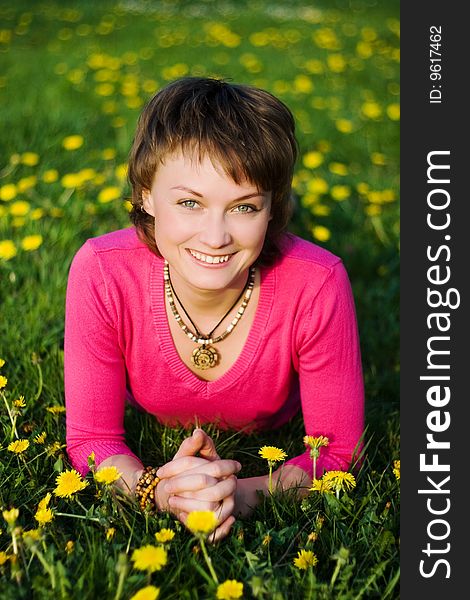 A young cheerful woman having fun on a dandelions glade