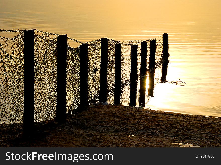 Fence shot on a shore of Dead Sea , Israel in sunrise light. Fence shot on a shore of Dead Sea , Israel in sunrise light