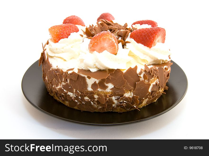 Whole strawberry gateau on a black plate with a white background