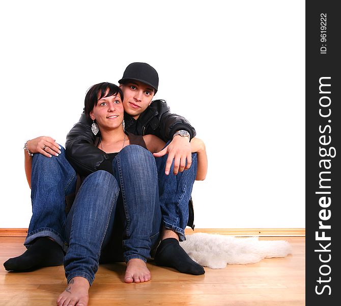 Young couple in hiphop / emo style sitting on the floor barefeet. Isolated over white.