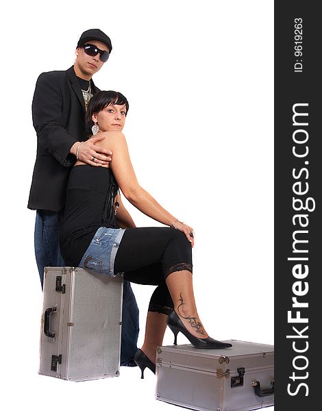 Young stylish couple isolated over white. She is sitting on dj cases. Young stylish couple isolated over white. She is sitting on dj cases.