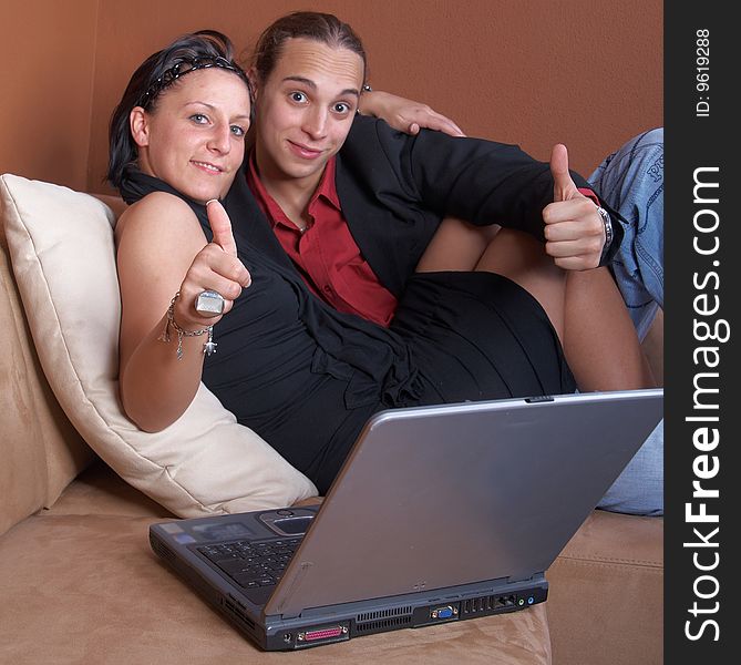 Young couple on the couch surfing the web with their laptop.