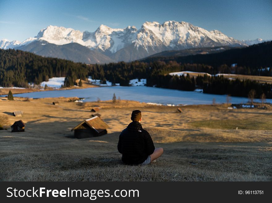 Hiker sitting on shores of alpine lake in Bavaria, Germany on sunny day,. Hiker sitting on shores of alpine lake in Bavaria, Germany on sunny day,