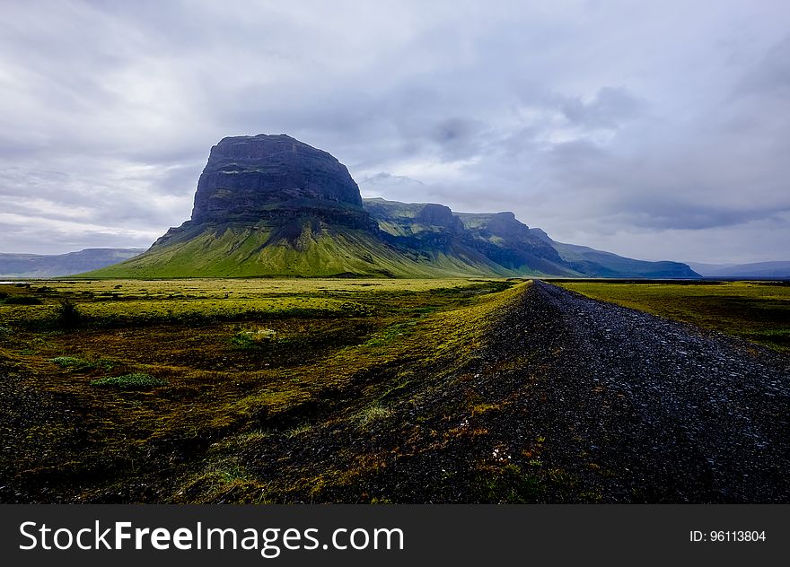 Rock formation in green rural field against cloudy skies in daytime. Rock formation in green rural field against cloudy skies in daytime.