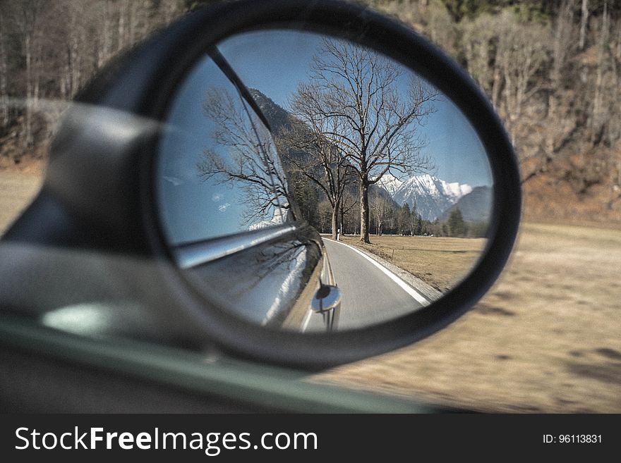 Mountains and trees reflecting in rear view mirror on car on sunny day. Mountains and trees reflecting in rear view mirror on car on sunny day.