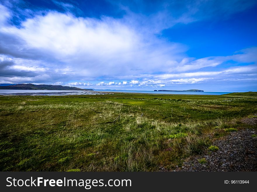 A landscape with green fields and mountains in the distance.