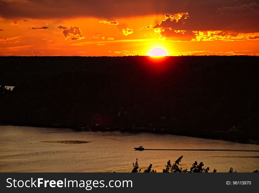 A high vantage point view over water with sun setting in the distance. A high vantage point view over water with sun setting in the distance.
