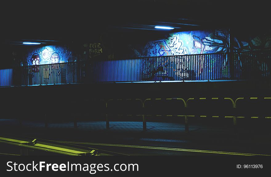 A view of a street at night with graffiti on the walls lit by the streetlights. A view of a street at night with graffiti on the walls lit by the streetlights.