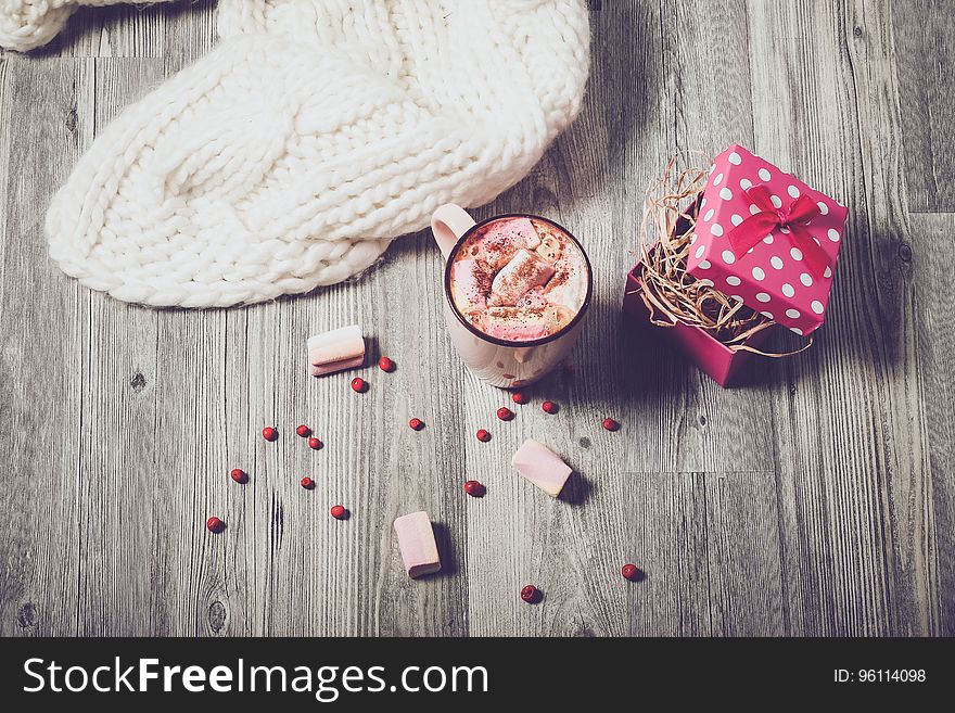 Overhead view of coffee with marshmallows, open gift box and white fabric on wooden background. Overhead view of coffee with marshmallows, open gift box and white fabric on wooden background.