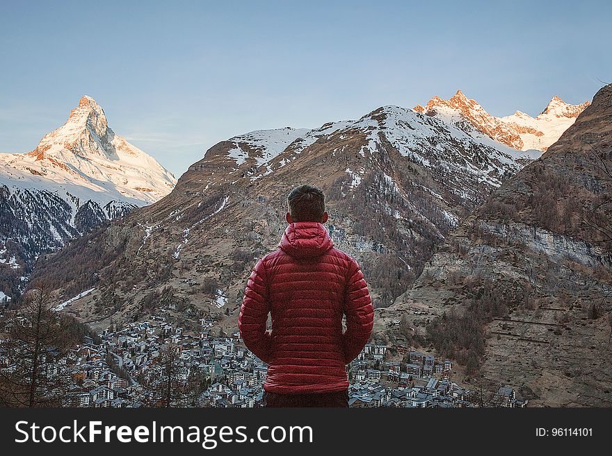A traveler looking over a valley and a mountain peak. A traveler looking over a valley and a mountain peak.