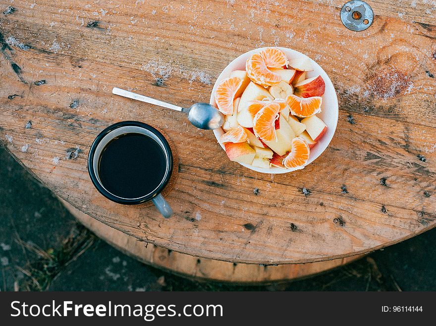 A cup of coffee with a bowl of fruit salad on a cable drum. A cup of coffee with a bowl of fruit salad on a cable drum.