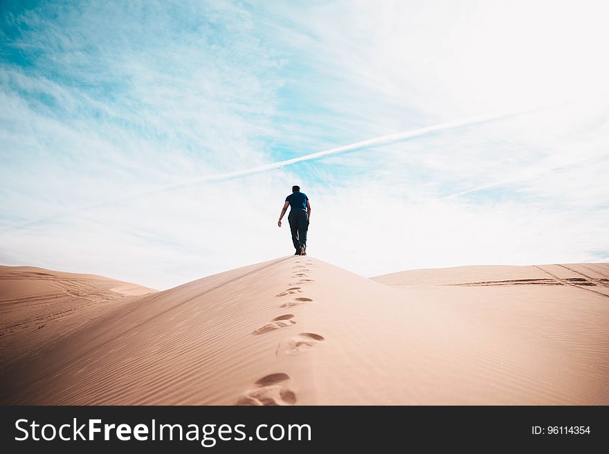 A man walking on a sand dune. A man walking on a sand dune.