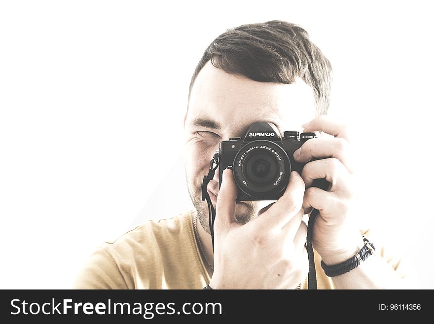 Portrait closeup of a young male adult looking through the viewfinder and adjusting the lens of his camera, isolated on a white background. Portrait closeup of a young male adult looking through the viewfinder and adjusting the lens of his camera, isolated on a white background.